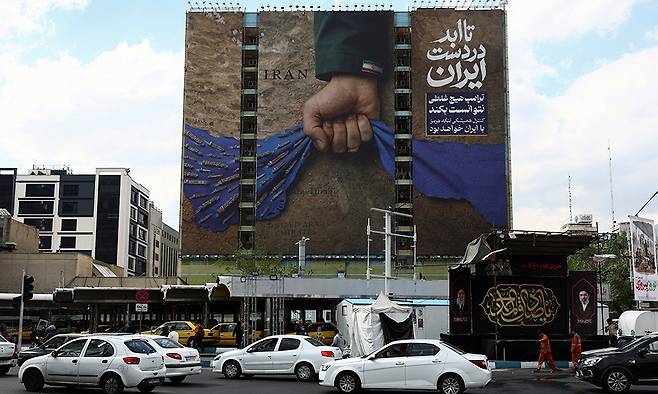 이란 “호르무즈 해협은 우리 것” 13일(현지시간) 이란 수도 테헤란 거리에 설치된 호르무즈해협 통제 의지를 담은 대형 광고판 앞을 자동차들이 지나가고 있다. 광고판 상단에는 “트럼프는 아무것도 할 수 없다. 호르무즈해협의 영원한 통제권은 이란에 있다”는 내용의 글이 적혀 있다. 이란의 호르무즈해협 봉쇄와 미국의 역봉쇄가 맞서면서 국제사회 우려가 커지고 있다. 테헤란=로이터연합뉴스