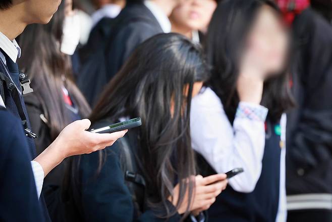 서울 시내 한 중학교에서 하교하는 학생들이 스마트폰을 사용하는 모습. 연합뉴스