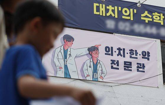 지난해 5월 서울 강남구 대치동 의대 입시학원 현수막 아래로 유치원생이 걸어가고 있다. 뉴스1