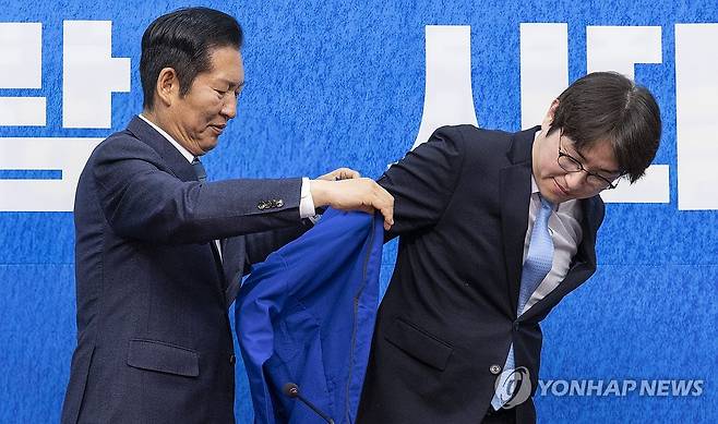 민주당 '파란 점퍼' 입는 하정우 전 AI수석 (서울=연합뉴스) 황광모 기자 = 6·3 재보선에 격전지로 떠오른 부산 북구 갑 지역구에 출마할 것으로 예상되는 하정우 전 청와대 AI수석이 29일 국회에서 열린 더불어민주당 인재 영입식에서 정청래 대표에게 민주당의 상징 '파란 점퍼'를 전달받아 입고 있다. 2026.4.29 hkmpooh@yna.co.kr