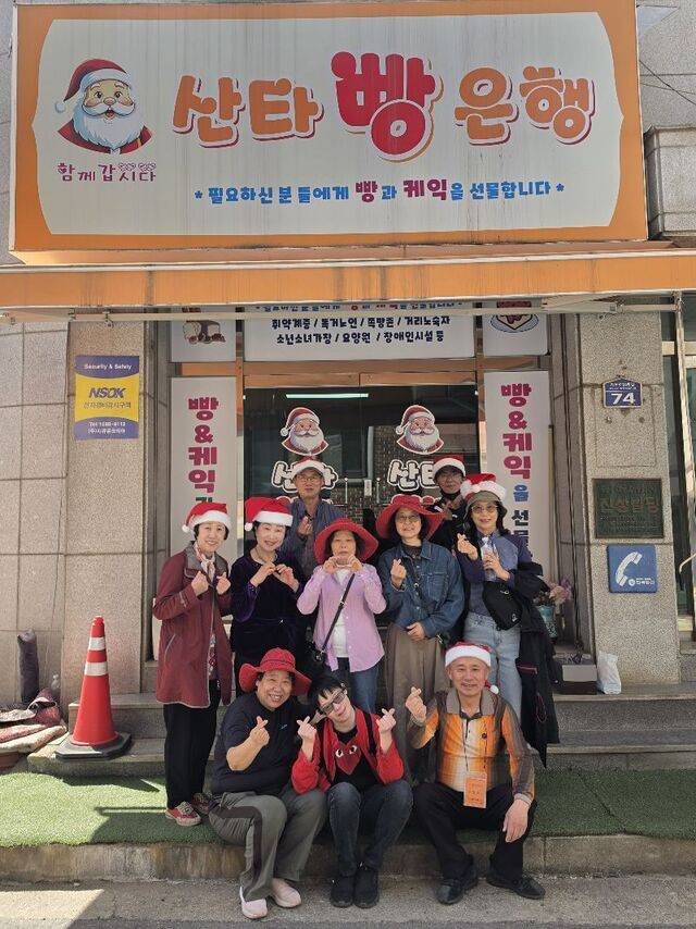 김병록 권점득(앞줄) 부부와 아들 다니엘(앞줄 가운데)씨, 산타빵은행 봉사자들이 지난 18일 경기도 고양의 산타빵은행 앞에서 봉사를 마친 뒤 기념촬영을 하고 있다. 가족 제공