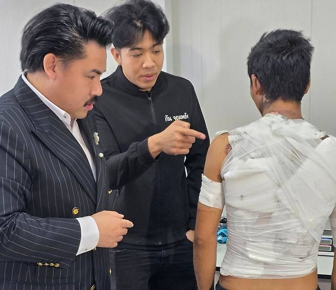 사회활동가 군터치 퐁파이분웻과 관계자가 온몸에 붕대를 감은 미안먀 출신 통역사 타타의 상체를 살펴보고 있다. 사진=방콕포스트