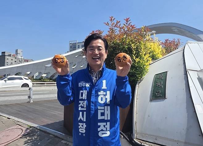 허태정 더불어민주당 대전시장 후보가 지난 13일 선거캠프가 있는 으능정이 거리의 목척교 앞에서 6·3 지방선거를 앞두고 출시한 ‘성심당 선거빵’을 양손에 들고 웃고 있다. 성심당 본점도 으능정이 거리에 있다. 최예린 기자