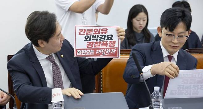 18일 국회에서 열린 행정안전위원회 전체회의에서 국민의힘 박수민(왼쪽)과 박충권 의원이 정원오 더불어민주당 서울시장 후보 폭행 사건의 의혹이 쓰여진 손팻말을 떼어내고 있다. 연합뉴스