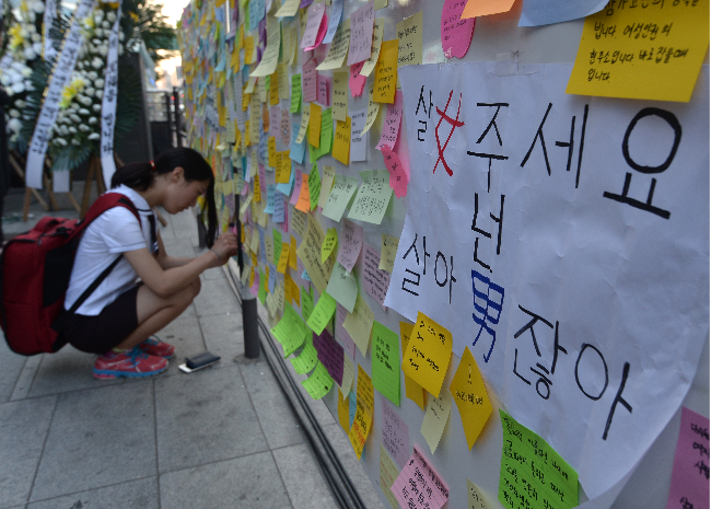 A student writes a message of condolence at a memorial for a woman killed in a stabbing near Gangnam Station in Gangnam-gu, Seoul, on May 19, 2016. (Newsis)