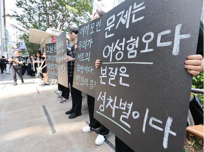 Participants of a memorial rally hold placards reading "The problem is misogyny. The essence is sexual discrimination," near Exit 10 of Gangnam Station in Seoul, marking 10 years since a woman was killed near the station. (Yohhap)