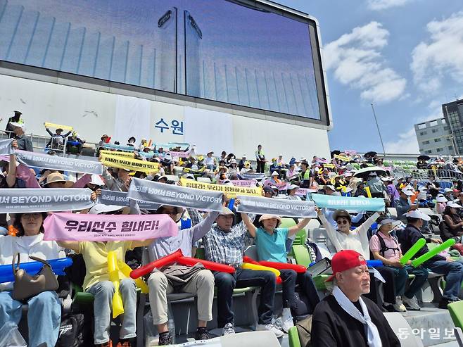 북한 내고향여자축구단을 응원하는 공동응원단이 23일 경기 수원시 수원종합운동장에서 선수들에 대한 응원 메시지가 전힌 수건을 펼쳐 들고 있다. 수원=권오혁 기자 hyuk@donga.com