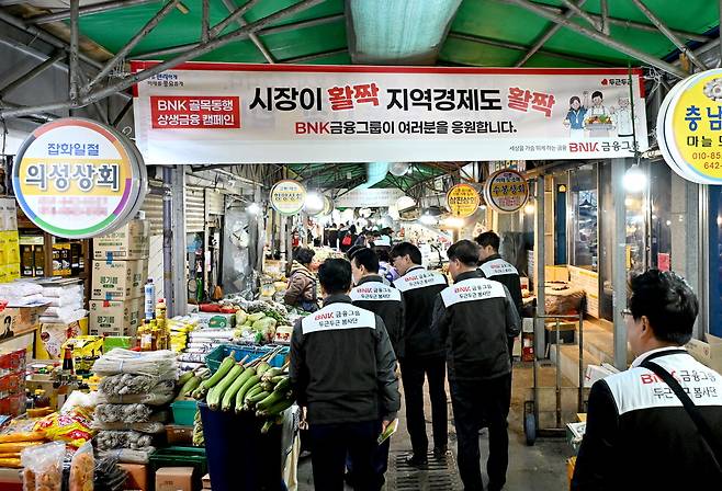 BNK금융그룹 임직원들이 지난 3월 부산의 한 전통시장을 방문해 상인들을 응원하는 차원에서 물건을 구매하고 있다. BNK금융