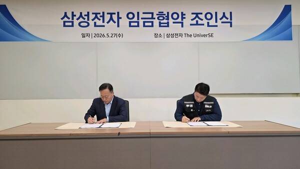 27일 용인시 기흥 삼성전자 The UniverSE에서 열린 2026년 임금협약 조인식에서 여명구 삼성전자 부사장(왼쪽)과 최승호 삼성그룹 초기업노동조합 삼성전자지부 위원장이 협약서에 사인하고 있다. <삼성전자 제공>