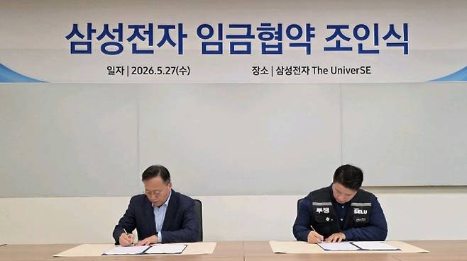 여명구 삼성전자 DS부문 피플팀장 부사장(왼쪽)과 최승호 삼성그룹 초기업노동조합 삼성전자지부 위원장이 27일 경기 용인시 삼성전자 The UniverSE에서 진행된 2026년 삼성전자 임금협약 조인식에서 서명을 하고 있다. / 사진=삼성그룹 초기업 노동조합 삼성전자지부