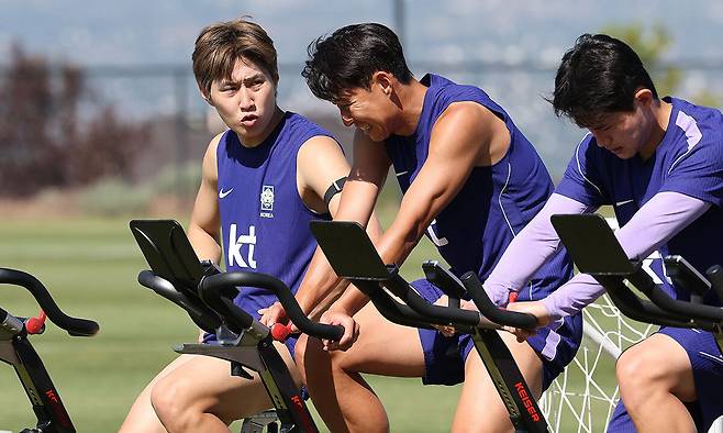 가볍게 몸푸는 ‘슛돌이’ 이강인(왼쪽)이 2일 한국 축구대표팀 2026 북중미 월드컵 사전캠프가 마련된 미국 유타주 솔트레이크시티 인근 헤리먼의 자이언스 뱅크 트레이닝센터에 합류해 손흥민(가운데)과 함께 이야기를 나누며 고정사이클을 타고 있다. 헤리먼=뉴시스
