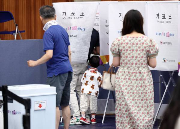 제9회 전국동시지방선거일인 3일 서울 잠전초등학교 체육관에 마련된 잠실본동 제4,5,6투표소에서 한 어린이가 투표하는 아빠를 보고 있다. 연합뉴스