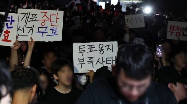 제9회 전국동시지방선거 및 국회의원 재·보궐선거 투표용지 부족으로 투표 시간이 오후 10시까지 연장됐던 서울 송파구 잠실7동 제2투표소 앞에서 4일 새벽 '부정선거' 등 손팻말을 든 시민들이 구호를 외치고 있다. 2026.6.4 연합뉴스