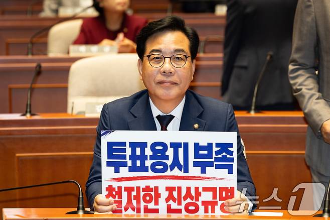 송언석 국민의힘 원내대표가 4일 서울 여의도 국회에서 열린 긴급 의원총회에 참석해 '투표용지 부족 철저한 진상규명'이라고 쓰여진 손팻말을 취재진을 향해 들어보이고 있다. 2026.6.4 ⓒ 뉴스1 유승관 기자