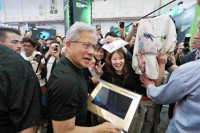 삼성디스플레이가 대만 타이베이 난강 전시장을 방문한 젠슨 황으로부터 노트북용 14형 OLED 패널에 사인을 받는 모습. 삼성디스플레이는 이번 '컴퓨텍스 2026'에서 엔비디아와 협력해 화질 체험존을 운영하고 있다.(공동취재단)