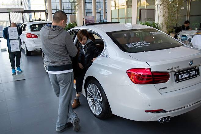 중국 베이징의 한 BMW 매장에서 고객들이 전시된 차량을 살펴보고 있다. (사진=AFP)