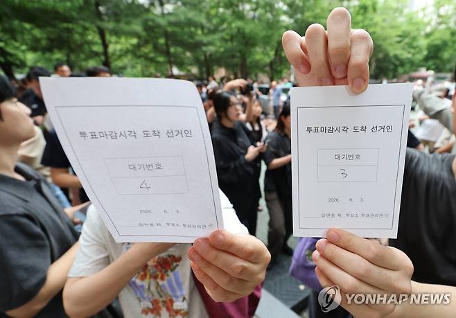 투표 대기번호표 (서울=연합뉴스) 김주형 기자 = 6·3 지방선거 본투표일인 3일 서울 송파구 잠실2동 6투표소에서 투표용지 부족으로 대기하던 한 유권자들이 마감시간 후 대기번호표를 들어 보이고 있다. 2026.6.3 kjhpress@yna.co.kr
