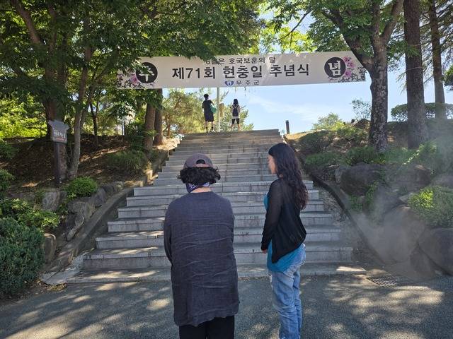 6일 현충일을 맞아 무주산골영화제 관람객 모녀가 바쁜 티켓팅 시간을 멈추고 묵념하고 있다. 김효종 기자