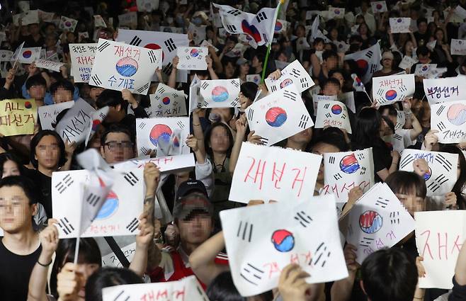 손으로 쓴 '재선거' 피켓 6·3 지방선거 투표용지 부족 사태에 항의하는 시민들이 7일 서울 송파구 올림픽공원 핸드볼경기장 앞에서 재선거를 요구하며 시위하고 있다. 상당수는 청년층으로, 이들은 손글씨로 '재선거'라고 적은 피켓과 태극기를 들고 자리를 지켰다. 김재훈 기자