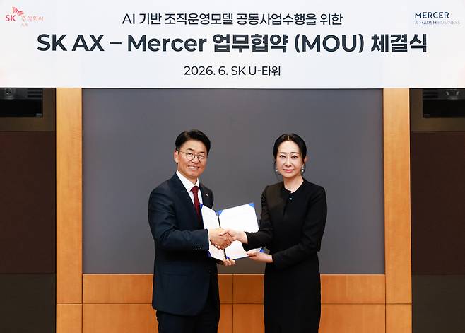 김완종 SK AX 사장(왼쪽)과 장지원 머서코리아 공동대표가 경기 성남 SK AX 본사에서 ‘AI+Human 조직 운영 모델 개발 및 에이전틱 AI 플랫폼 구축 공동 사업 수행 협약(MOU)’을 체결한 후 기념촬영을 하고 있다. SK AX