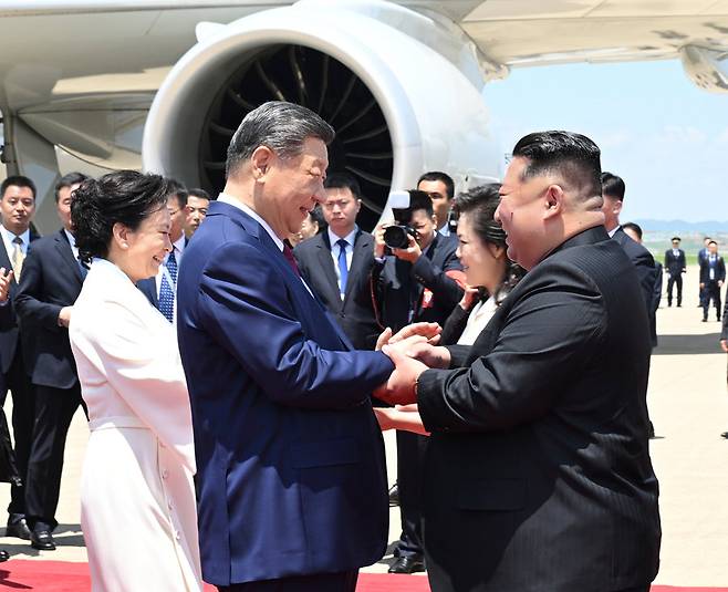 8일 북한 평양 순안공항에 도착한 시진핑 중국 국가주석(앞줄 왼쪽)과 김정은 북한 국무위원장(앞줄 오른쪽)이 환하게 웃으며 손을 맞잡고 있다. 시 주석의 부인 펑리위안 여사(뒷줄 왼쪽)와 김 위원장의 부인 리설주(뒷줄 오른쪽) 또한 남편들의 곁에서 인사하고 있다. 평양=신화망