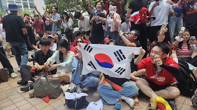 12일 오후 12시55분께 서울 영등포구 한국투자증권 앞에서 경기가 승리로 끝나자 응원단이 태극기를 들며 기뻐하고 있다. 이우중 수습기자