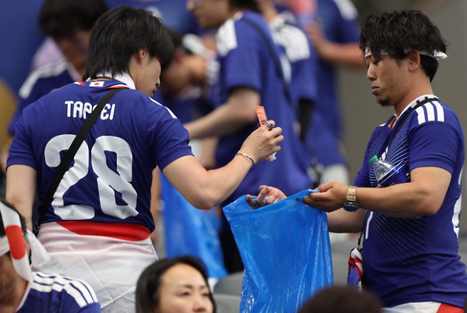 일본 축구팬들이 15일 미국 텍사스주 알링턴의 댈러스 스타디움에서 열린 2026 북중미 월드컵 조별리그 F조 네덜란드와 일본의 경기가 끝난 뒤 관중석에 남은 쓰레기를 수거하고 있다. AFP연합뉴스