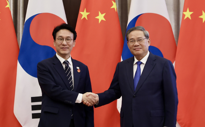 김민석 총리가 중국 방문 기간 리창 중국 국무원 총리와 만나 기념촬영을 하고 있다. 이 일정에서는 태극기 배지가 정상 방향으로 착용된 모습이 확인된다. (총리실)