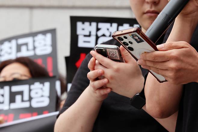 일면식 없는 이채원양을 거리에서 흉기로 살해한 장윤기의 첫 재판이 있는 지난달 22일 광주 동구 광주지방법원 앞에서 열린 장윤기 엄벌 촉구 기자회견에 참석한 유가족 휴대전화에 고 이채원 양의 사진이 붙어있다. 연합뉴스