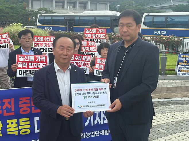 6일 오전 청와대 분수광장에서 열린 'CPTPP 가입 추진 중단 촉구 및 농산물 가격 폭락·농자재값 폭등 대책 요구' 기자회견에서 노만호 한종협 회장이 농업계 요구 건의문을 청와대 농림축산비서관실 김형식 행정관에게 전달하고 있다.