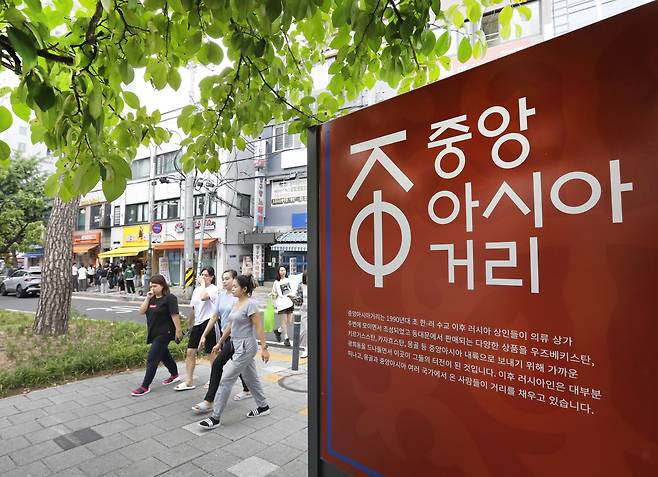 People walk past a signboard explaining Central Asia Street. PARK SANG-MOON