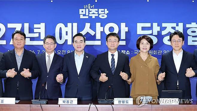 2027년 예산안 당정, 기념촬영 (서울=연합뉴스) 배재만 기자 = 더불어민주당 한병도 직무대행 겸 원내대표(왼쪽 네 번째)와 박홍근 기획예산처 장관(왼쪽 세 번째)이 21일 국회 의원회관에서 열린 2027년 예산안 당정 협의에서 손을 잡고 기념 촬영을 하고 있다. 왼쪽부터 이광재 예결위원장, 기획예산처 조용범 차관, 박홍근 장관, 더불어민주당 한병도 대표 직무대행 겸 원내대표, 한정애 정책위의장, 천준호 원내운영수석부대표. 2026.7.21 scoop@yna.co.kr