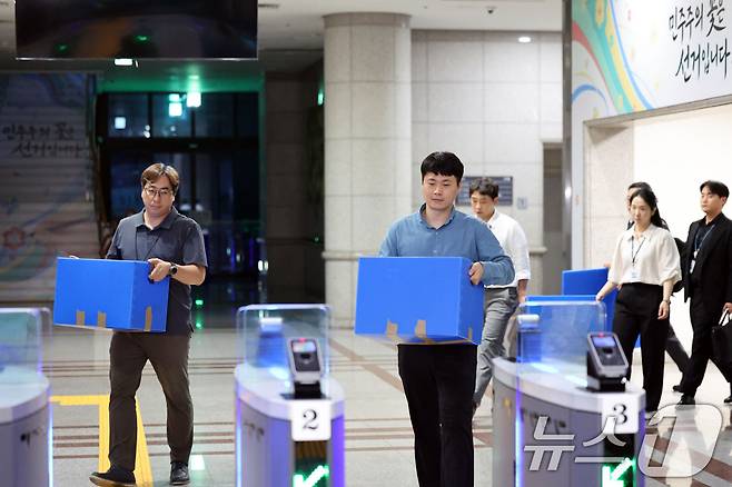 6·3 지방선거 투표용지 부족 사태를 수사 중인 검·경 합동수사본부 관계자들이 23일 오후 경기 과천시 중앙선거관리위원회에 대한 압수수색을 마친뒤 압수상자를 들고 나서고 있다. (공동취재) 2026.7.23 ⓒ 뉴스1 이광호 기자
