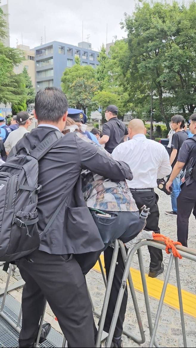 펜스를 넘는 우익단체 회원 (도쿄=연합뉴스) 이도연 특파원 = 15일 '야스쿠니 해체' 시위자를 위협하기 위해 펜스를 넘는 우익단체 회원. 2026.8.15.