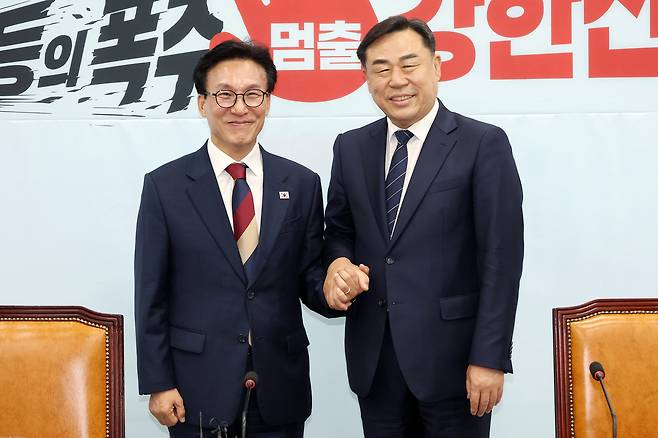 더불어민주당 김민석 대표가 24일 국회에서 진보당을 예방해 김종훈 대표와 손을 맞잡고 있다. 연합뉴스