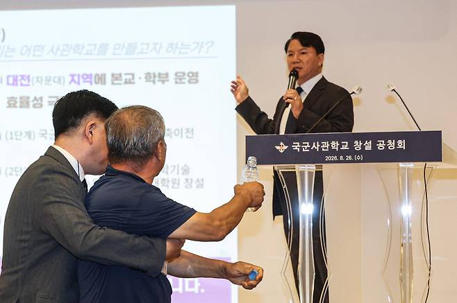 26일 오후 서울 용산구 국방컨벤션에서 열린 국군사관학교 창설 공청회에서 한 참석자가 발언하고 있는 김홍철 국방부 정책실장에게 생수병을 든 채 다가서고 있다. (공동취재) 2026.8.26 뉴스1