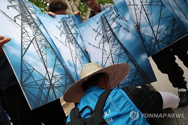 송전탑 안에 갇힌 농민 (서울=연합뉴스) 김성민 기자 = 고압송전선로·철탑건설반대영암군대책위원회가 7일 서울 종로구 청와대 앞에서 연 신해남-신장성 345kV 송전선로 철회 촉구 결의대회에서 참가자들이 송전탑 손팻말을 들고 퍼포먼스를 하고 있다. 2026.7.7 ksm7976@yna.co.kr