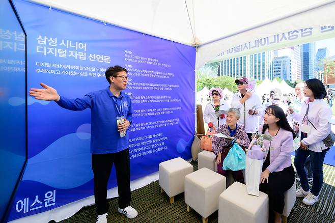 서울광장에 마련된 삼성 시니어 디지털 아카데미(SSDA) 교육 부스에서 지난해 6월 한 강사가 교육생들을 대상으로 프로그램을 설명하고 있다. 에스원 제공
