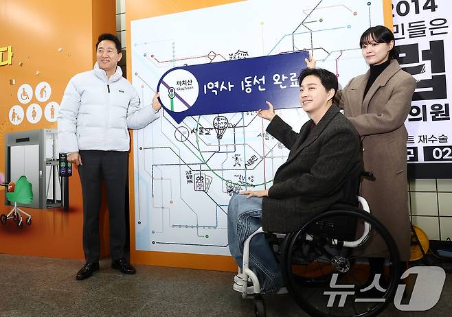 오세훈 서울시장이 29일 오후 서울 강서구 까치산역에서 열린 전역사 1역사 1동선 확보 기념행사에서 가수 송지은, 박위 부부와 함께 1역사 1동선 완료 피켓을 들고 기념촬영을 하고 있다. 2025.12.29 ⓒ 뉴스1 김민지 기자
