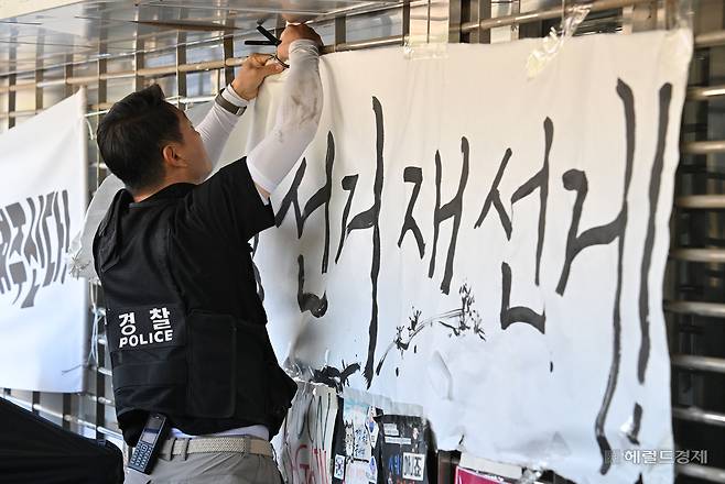 8일 오전 서울 송파구 올림픽공원 핸드볼경기장에서 한 경찰이 개표소에 진입하기 위해 현수막을 제거하고 있다. 이날 경찰은 오전 9시부터 2-3게이트 입구에 천막과 현수막을 철거한 뒤 6·3 지방선거 잠실 개표소 봉쇄 시위 95일 만에 진입에 성공했다. 임세준 기자