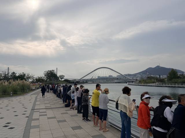 29일 오전 부산 북항 친수공원을 찾은 시민들이 수로를 따라 길게 늘어선 채 이날 외해 유도를 앞둔 상어