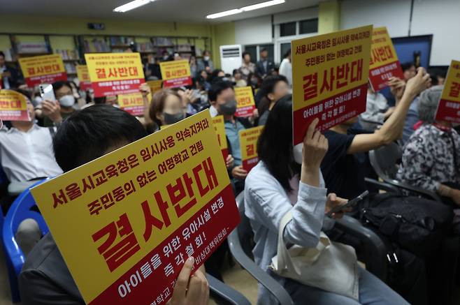 지난 17일 서울 강서구 여명학교에서 열린 옛 염강초등학교 부지 내 유아교육 진흥원과 여명학교 교사(校舍) 건립안에 대한 주민설명회에서 주민들이 여명학교 건립을 반대하는 손팻말을 들고 있다. 연합뉴스