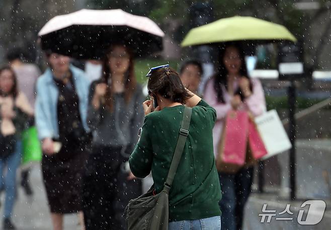 서울 중구 롯데백화점 본점 앞에서 시민들이 비를 피하며 이동하고 있다. 2026.10.12 ⓒ 뉴스1 김진환 기자