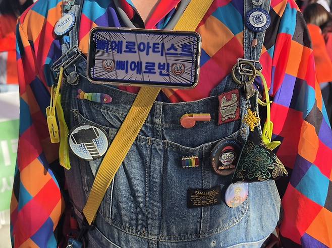 지난 14일 서울 용산구에서 만난 ‘삐에로빈’ 신승빈씨의 멜빵 바지에 며칠 전 경북 영천의 한 축제에서 “고생한다”며 받은 복주머니, 거래 업체 사장이 사은품으로 준 빨래집게, 카이스트와 서울대 배지 등이 매달려 있다. 배지를 어디서 얻었는지는 그도 기억하지 못했다. 백재연 기자