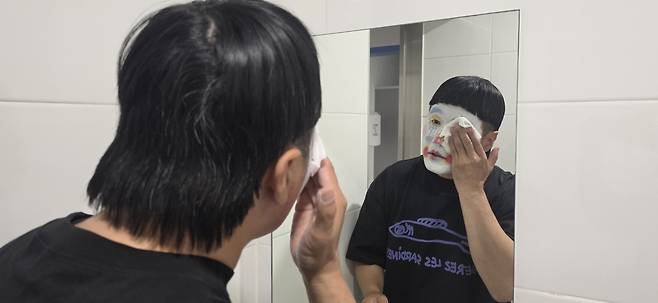행사를 마친 신씨가 화장실 거울 앞에서 클렌징 티슈로 백분을 닦아내고 있다. 유성 분장은 여러 번 닦아도 쉽게 지워지지 않는다. 백재연 기자