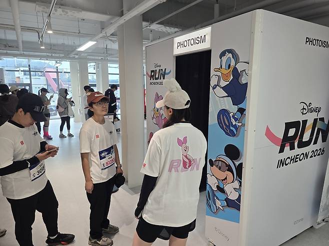 24일 인천 상상플랫폼에서 열린 ‘디즈니런 2026’ 행사장에서 참가자들이 디즈니 캐릭터로 꾸며진 즉석 사진 부스 ‘포토이즘’을 이용하기 위해 대기하고 있다. 이진석 기자